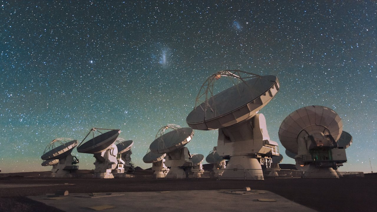 Mehrere weiße Antennenschüsseln unter einem Sternhimmel